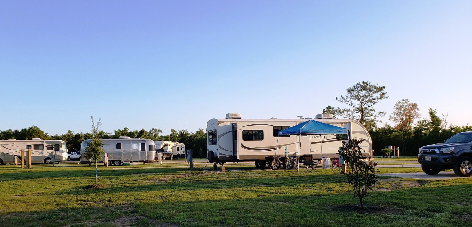 RVs parked on green grass sites at Liverpool RV Park at sunset